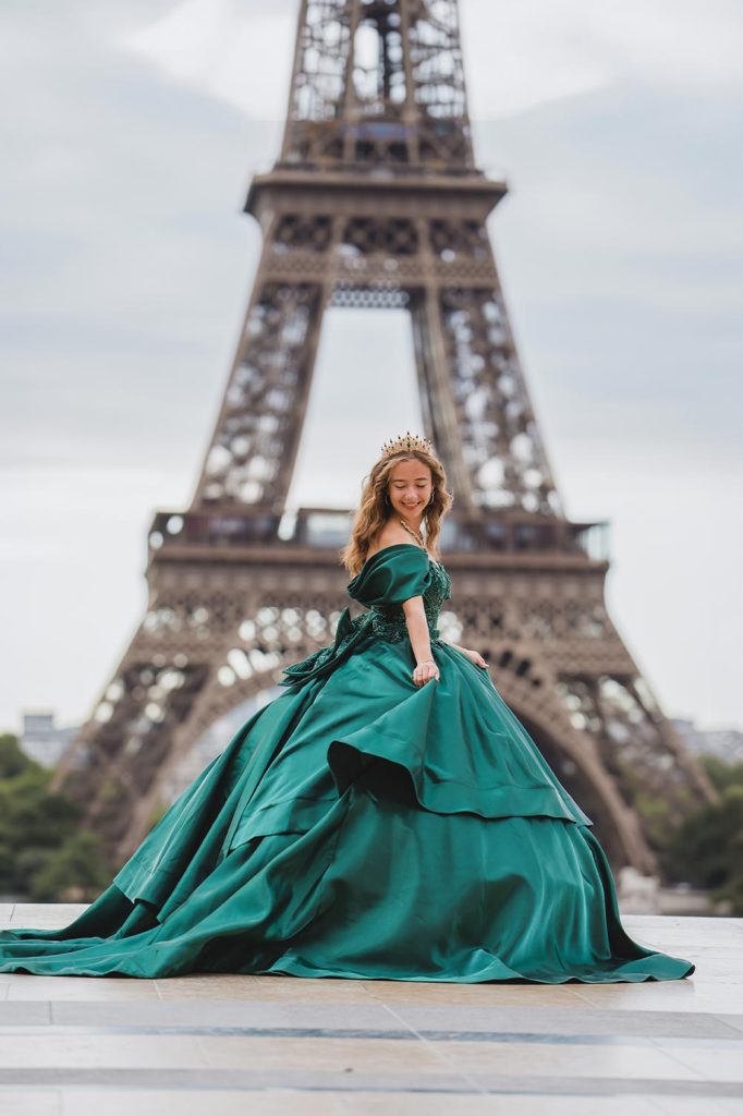 Quinceañera en París con vestido verde esmeralda y corona frente a la Torre Eiffel / Quinceañera in Paris wearing an emerald green gown and crown in front of the Eiffel Tower