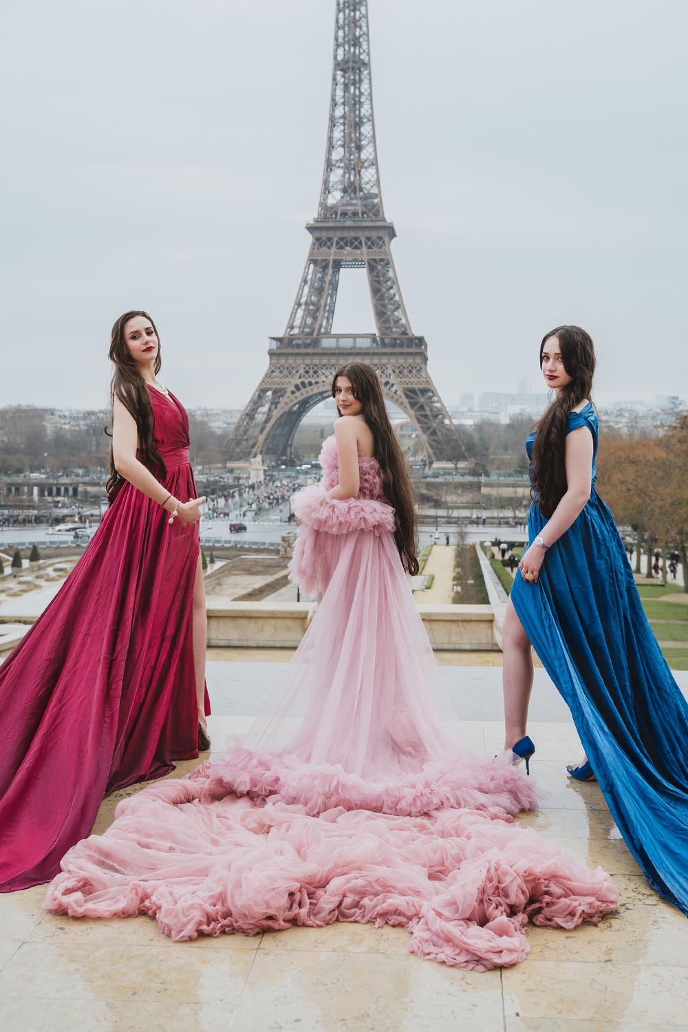 Tres jóvenes con vestidos rojo, rosa y azul frente a la Torre Eiffel en el Trocadéro, París / Three young women in red, pink, and blue gowns in front of the Eiffel Tower at the Trocadéro, Paris
