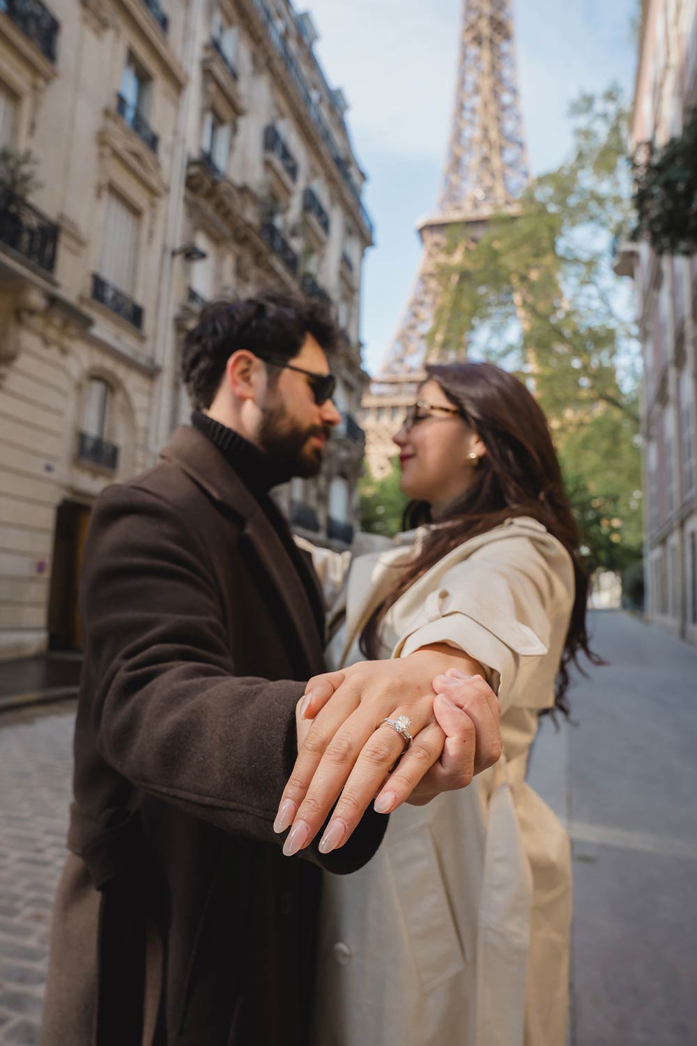 Pareja mostrando el anillo de compromiso en una calle parisina con la Torre Eiffel de fondo / Couple showing off the engagement ring on a Parisian street with the Eiffel Tower in the background